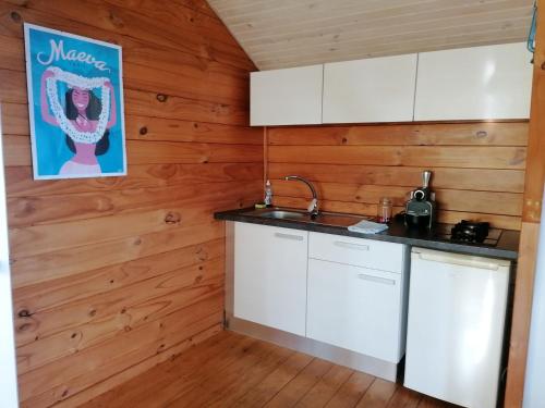 a kitchen with white cabinets and wooden walls at Bungalow Moemoea in Punaauia