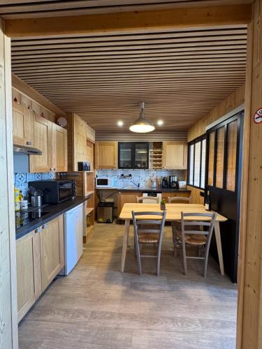 une cuisine avec des armoires en bois et une table et des chaises dans l'établissement Magnifique appartement 4-6 personnes au pied des pistes à La Plagne Centre, à La Plagne Tarentaise