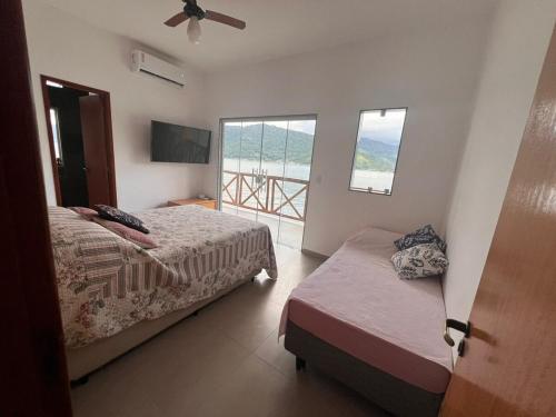 a bedroom with two beds and a balcony at Casa AMar Mangaratiba in Mangaratiba