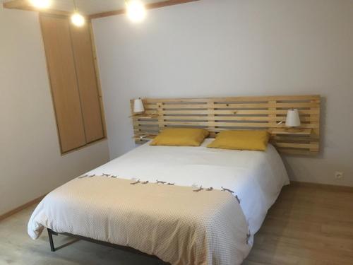 - une chambre avec un grand lit blanc et des oreillers jaunes dans l'établissement Magnanerie Leony 2, à Saint-Florent-sur-Auzonnet