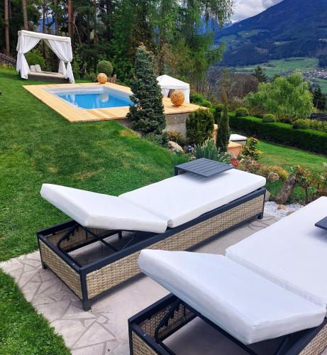a backyard with a pool and two lounge chairs at Boutique Pension Erlacher - Adults Only in Villandro