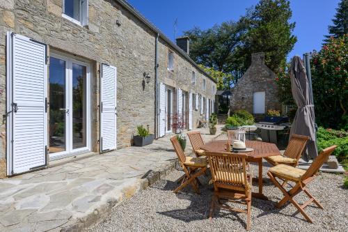 a patio with a table and chairs and an umbrella at Les 13 lavoirs d'antan - chambre zen attitude in Saint-Pierre-Église