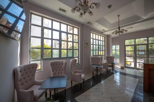 a waiting room with chairs and tables and windows at Hotel Ramses Ks in Golem