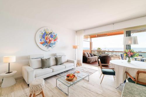 a living room with a white couch and a table at Emilie - panoramic sea views beach facing paradise in Vallauris