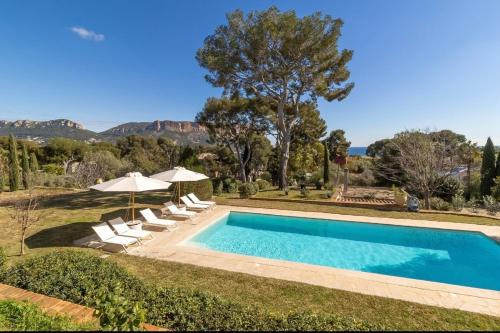 une piscine avec chaises et parasols dans une cour dans l'établissement La Roca Blanca, à Cassis