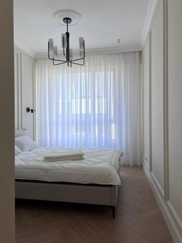 アルマトイにあるMeridian Apartmentsのベッドルーム1室(シャンデリア、窓付)