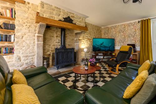 a living room with a green couch and a television at Les 13 lavoirs d'antan - chambre la belle époque in Saint-Pierre-Église