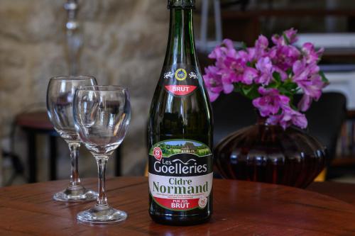 a bottle of wine and two glasses on a table at Les 13 lavoirs d'antan - chambre la belle époque in Saint-Pierre-Église