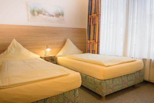a hotel room with two beds and a window at Parkhotel Friedrichstrasse in Gießen