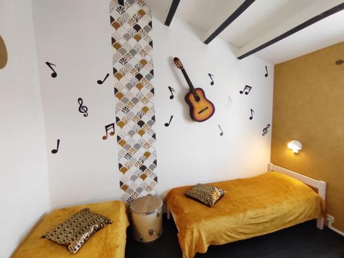 a room with two beds and a guitar on the wall at Village Bord de Ciel in Caylus