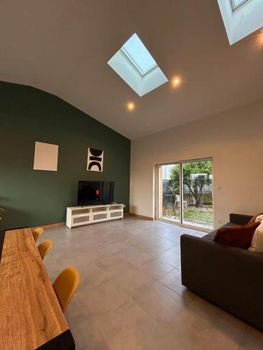 a living room with a couch and a tv and a table at Spacious house - garden, Netflix & shops in Béguey