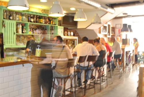 a group of people sitting at a bar in a restaurant at Hostal Kukia in Noya