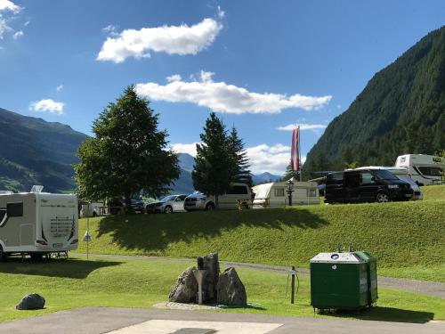 a group of vehicles parked in a field with mountains at Nationalpark-Camping Großglockner in Heiligenblut