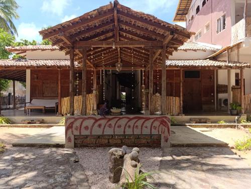 a pavilion with a bench in front of a house at Red Coral Village Kitesurfing School in Kalpitiya