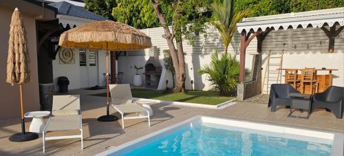 a swimming pool with chairs and an umbrella at Appartements Des Roses in Le Lamentin
