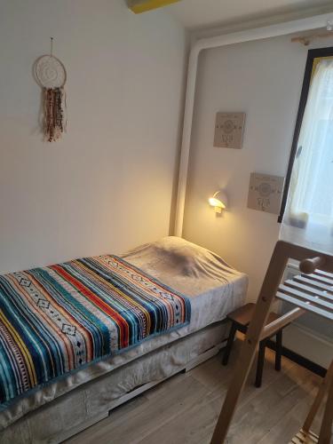 a small bedroom with a bed and a chair at Village Bord de Ciel in Caylus