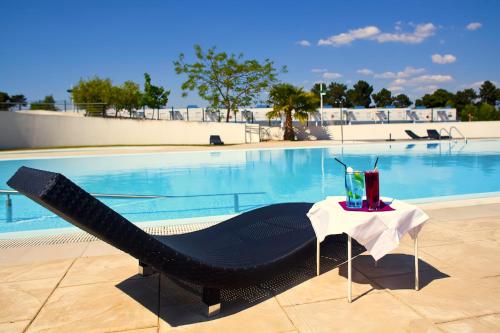 une chaise noire et une table à côté de la piscine dans l'établissement Arrábida Resort, à Quinta do Anjo