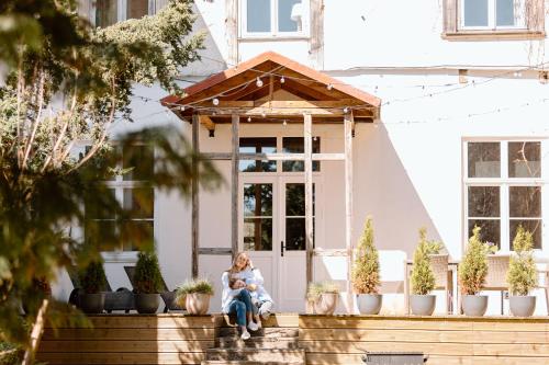 a woman sitting on the front porch of a house with a child at Black Princess in Cēsis