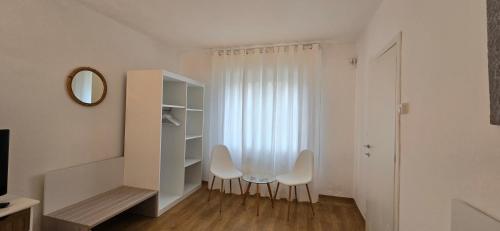 a white room with two chairs and a window at Confortevole Appartamento a Belluno in Belluno