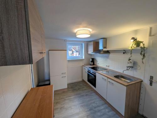 a small kitchen with white cabinets and a sink at Haus Haiderbach Nähe A3 in Wittgert
