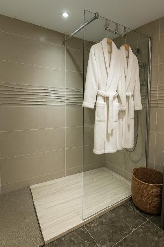 une salle de bain avec une cabine de douche en verre avec un peignoir dans l'établissement Logement cosy avec piscine et jacuzzi privé, à Poussan