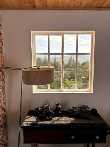 a table with a lamp and a window at The house in the mountains in Tinjacá