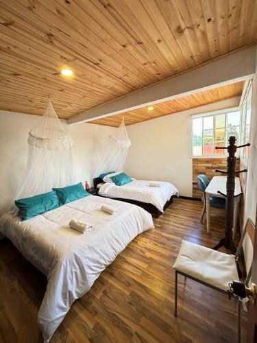 two beds in a room with wooden ceilings at The house in the mountains in Tinjacá