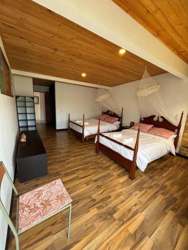 two beds in a room with a wooden ceiling at The house in the mountains in Tinjacá