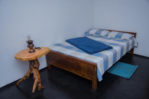 a small bed with a wooden table next to a wall at Blooming Rose Homestay in Ohiya