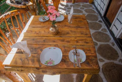 a wooden table with plates and a vase of flowers on it at Blooming Rose Homestay in Ohiya