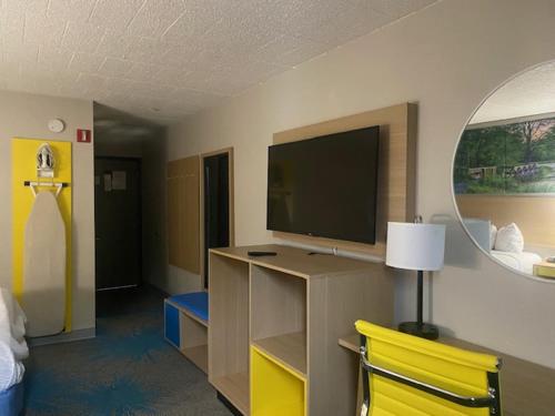 a hotel room with a tv and a yellow chair at Days Inn by Wyndham Scranton PA in Dickson City