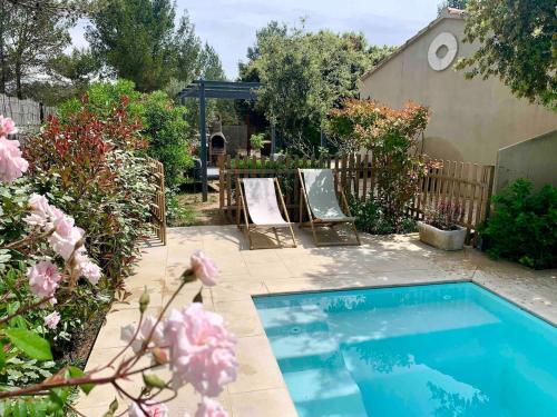 - une petite piscine dans une cour ornée de fleurs roses dans l'établissement La Pomme de Pin, à Eygalières