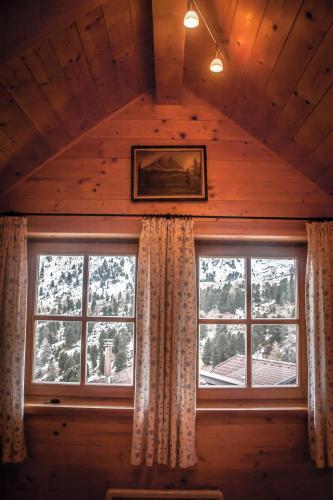 a room with two windows in a log cabin at Almhütte Falkert in Patergassen