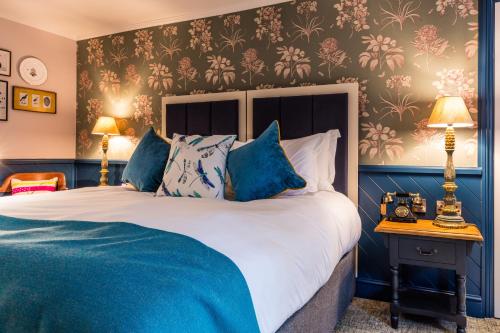 a bedroom with a large bed with blue walls at Hand and Spear in Weybridge