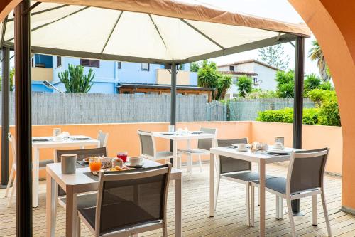 a patio with tables and chairs under an umbrella at Le Terrazze di Bellavista in Su Forti