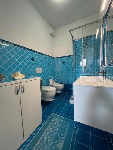a blue tiled bathroom with a sink and a toilet at Domus Strazza Porto Quadro in Santa Teresa Gallura