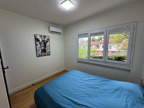 una camera con un letto blu e due finestre di Villa Nature à TOULOUSE a Tolosa