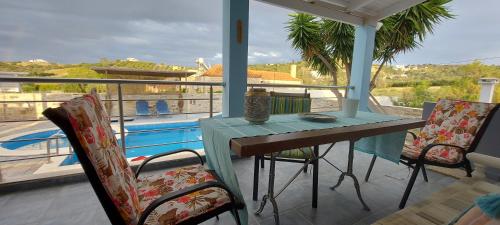a porch with a table and chairs and a pool at Villa Zahner in Pitsidia