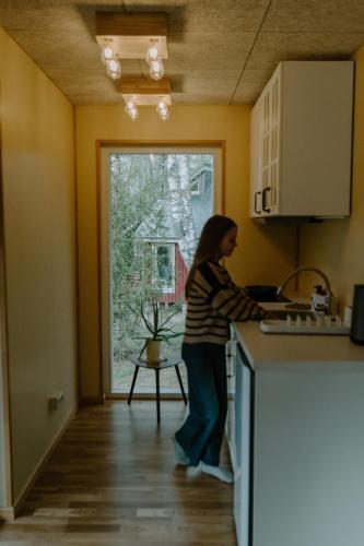 a woman standing at a counter in a kitchen at Rītu atpūtas namiņi in Talsi