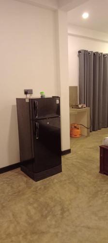 a kitchen with a black refrigerator in a room at The Nest in Weligama