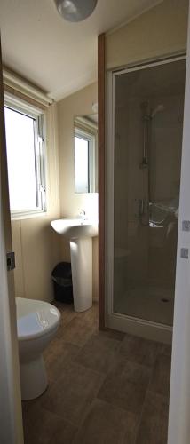 a bathroom with a shower and a toilet and a sink at Moonstone Hayling Island Holiday Park in South Hayling