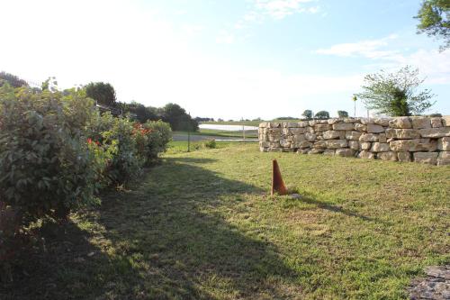 a garden with a stone wall and a cone at Maison proche centre village in Grignan