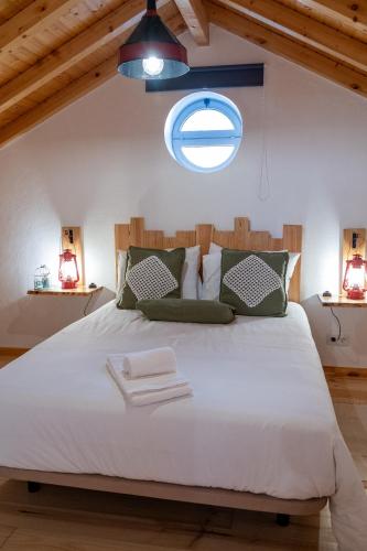 a bedroom with a large white bed with a window at Adega dos Avós - Casa completa in Alcobaça
