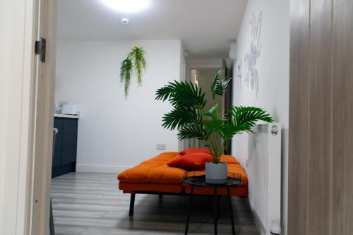 an orange couch with a plant on a table at Centrally Located Apartments in Cardiff