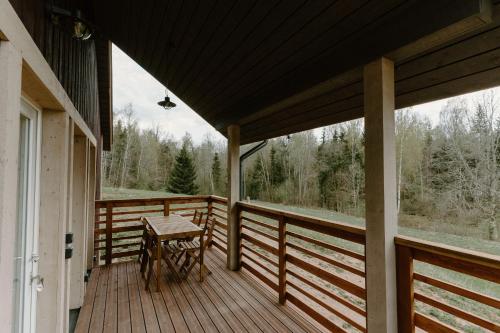 a porch with a table and a view of the woods at Rītu atpūtas namiņi in Talsi