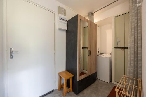 a bathroom with a door and a chair and a refrigerator at Nid Paisible - Balcon - Calme - Parking in Barcelonnette
