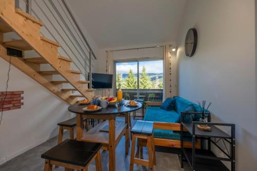 a living room with a table and chairs and a staircase at Nid Paisible - Balcon - Calme - Parking in Barcelonnette
