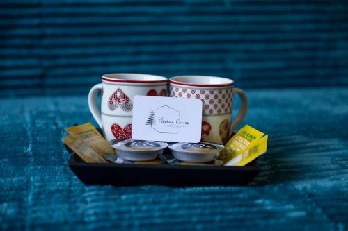 two coffee mugs sitting on a tray with cookies at Nid Paisible - Balcon - Calme - Parking in Barcelonnette