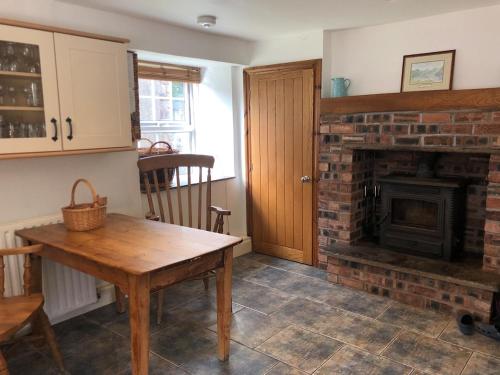 a living room with a brick fireplace and a wooden table at High House Cottage - A traditional home from home in St Bees