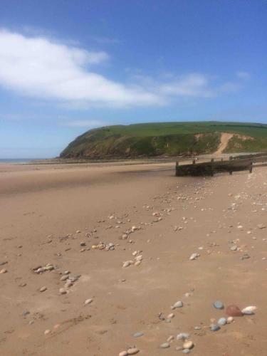 a beach with shells on the sand and a pier at High House Cottage - A traditional home from home in St Bees